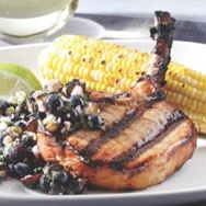 Teriyaki pork chops with blueberry-ginger relish and corn on a white plate