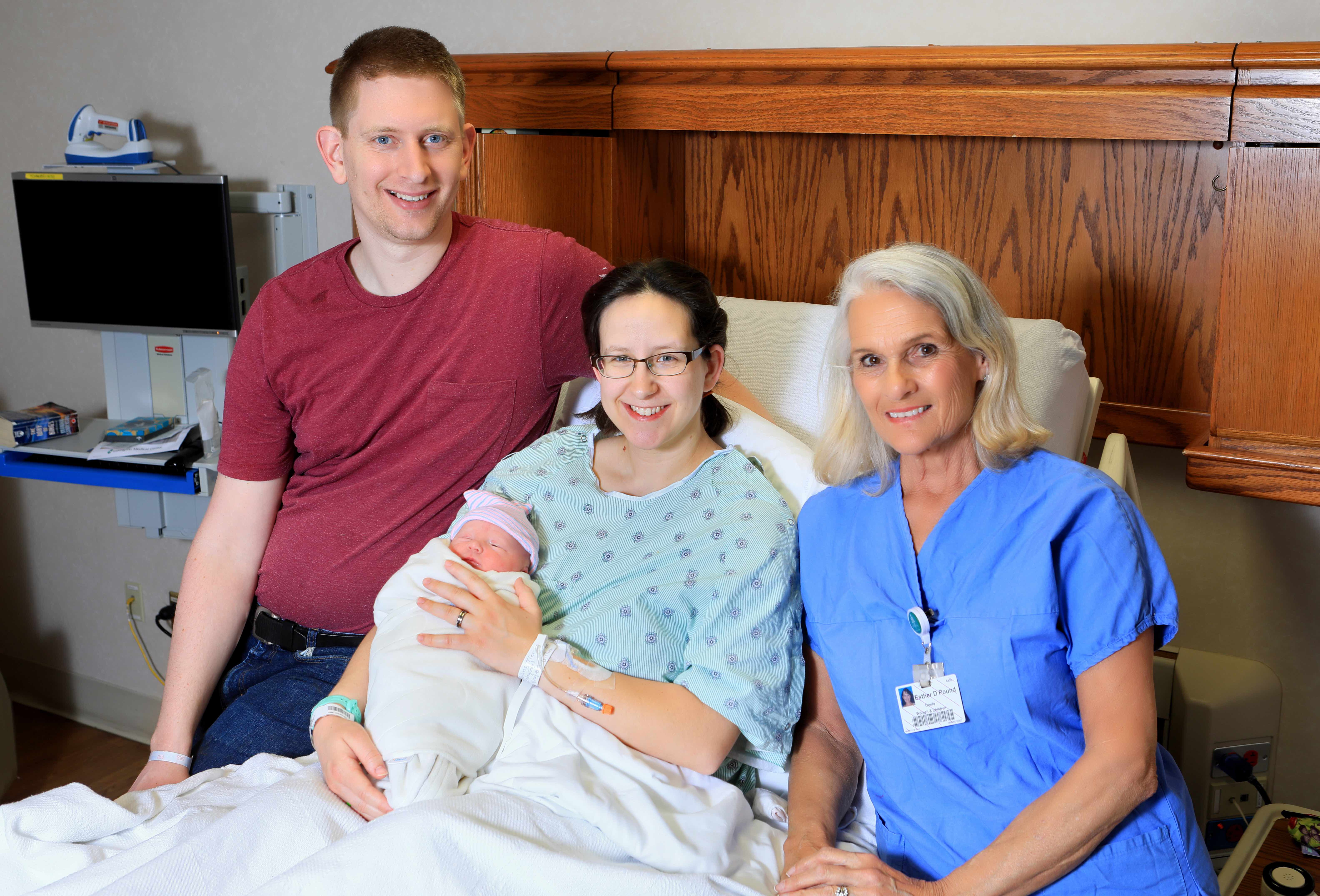 Doula next to a man and mother holding a newborn baby
