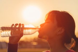 A woman drinking out of a water bottle during a workout.