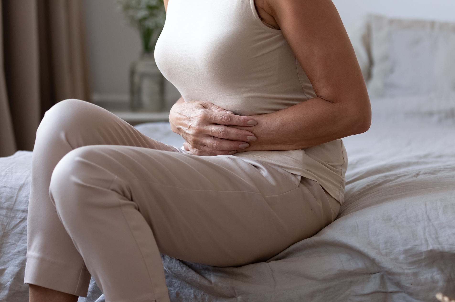 Woman on bed clutching her abdomen