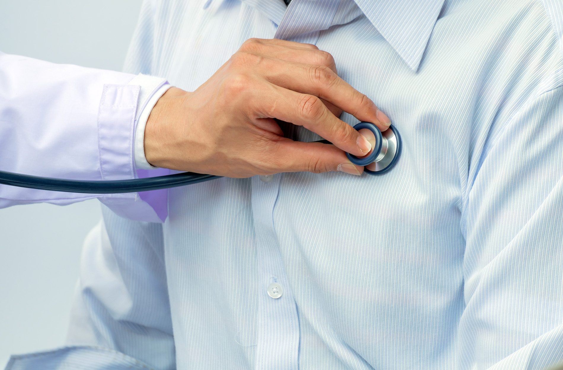 Doctor's hand holding stethoscope on patient's chest