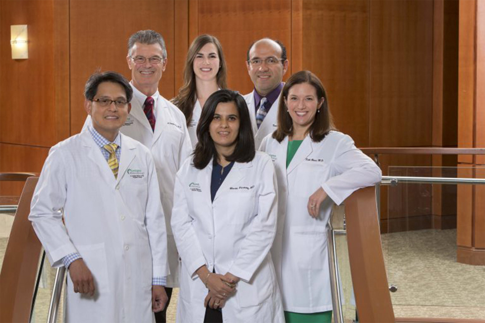 The six physicians of Lexington Rheumatology posing together on a small staircase in their lab coats.