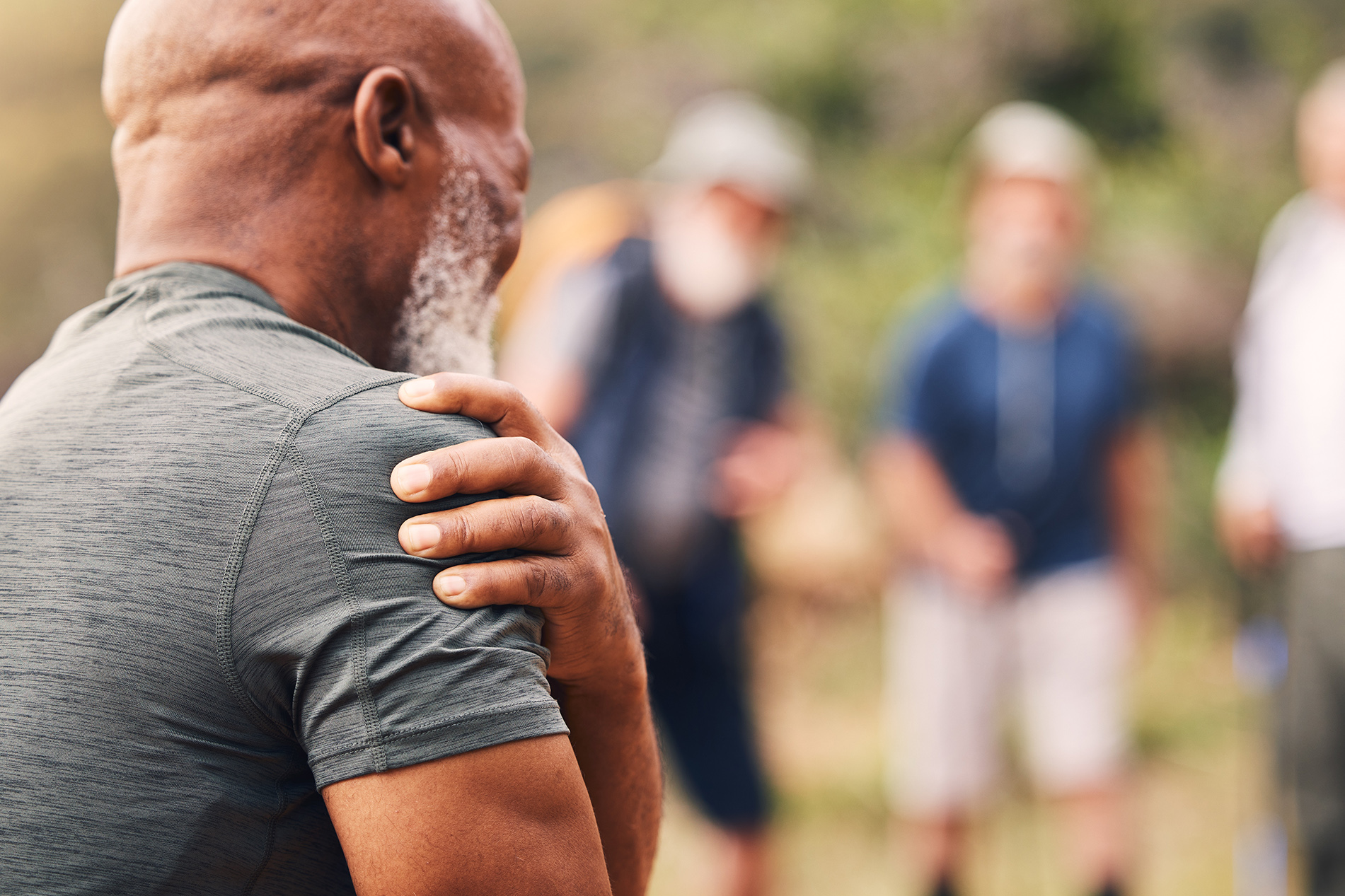 older black man gripping his shoulder