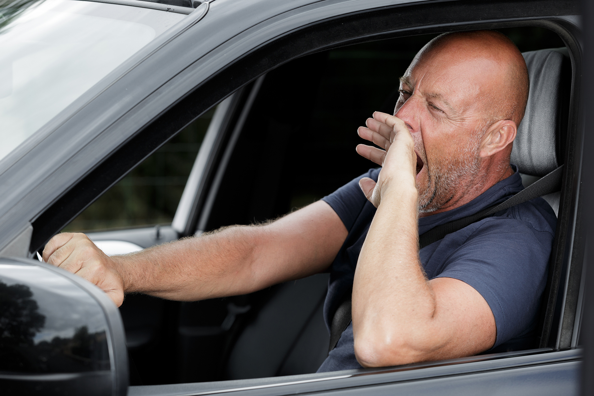 Man yawning in car