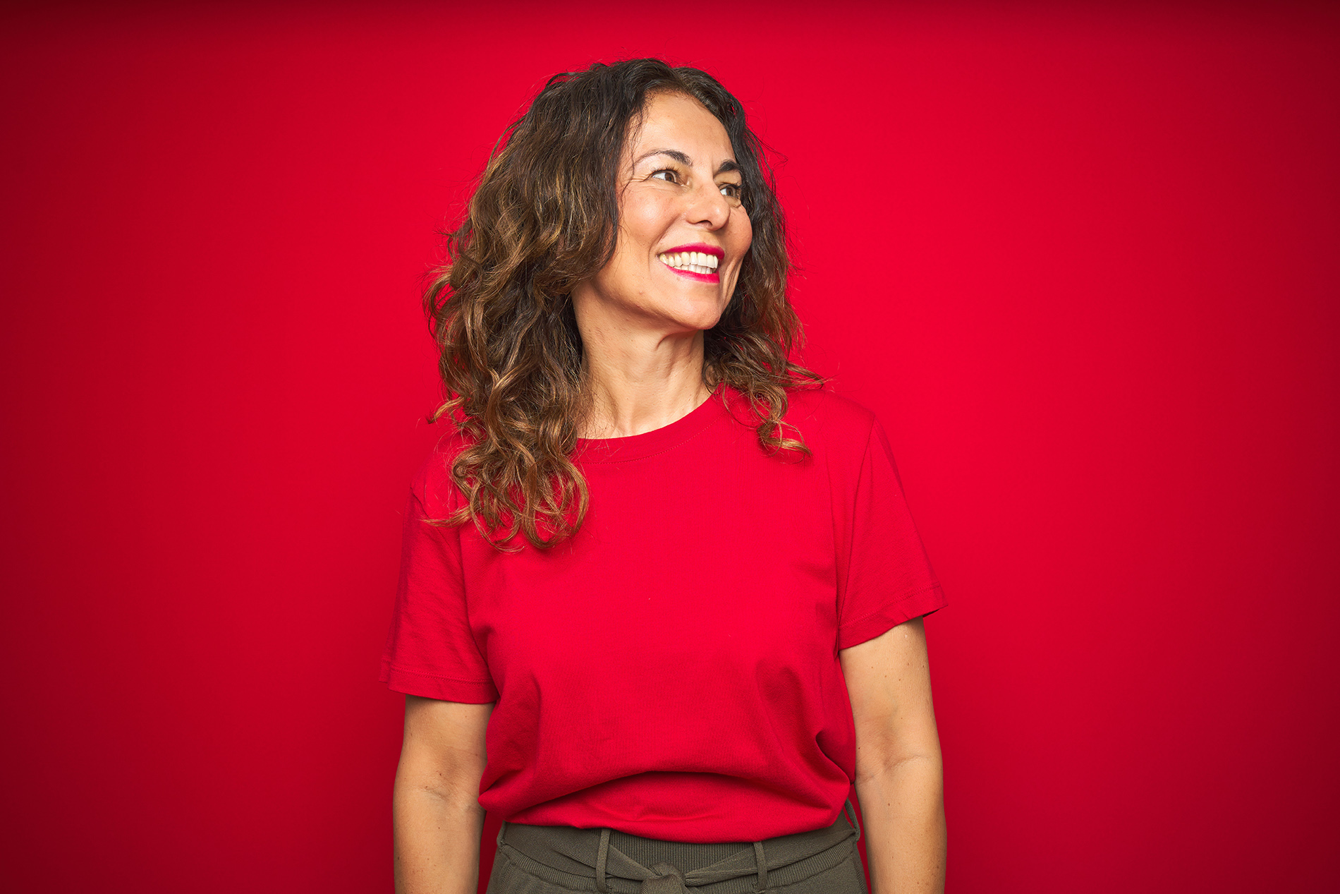 Middle aged woman smiling in front of red background