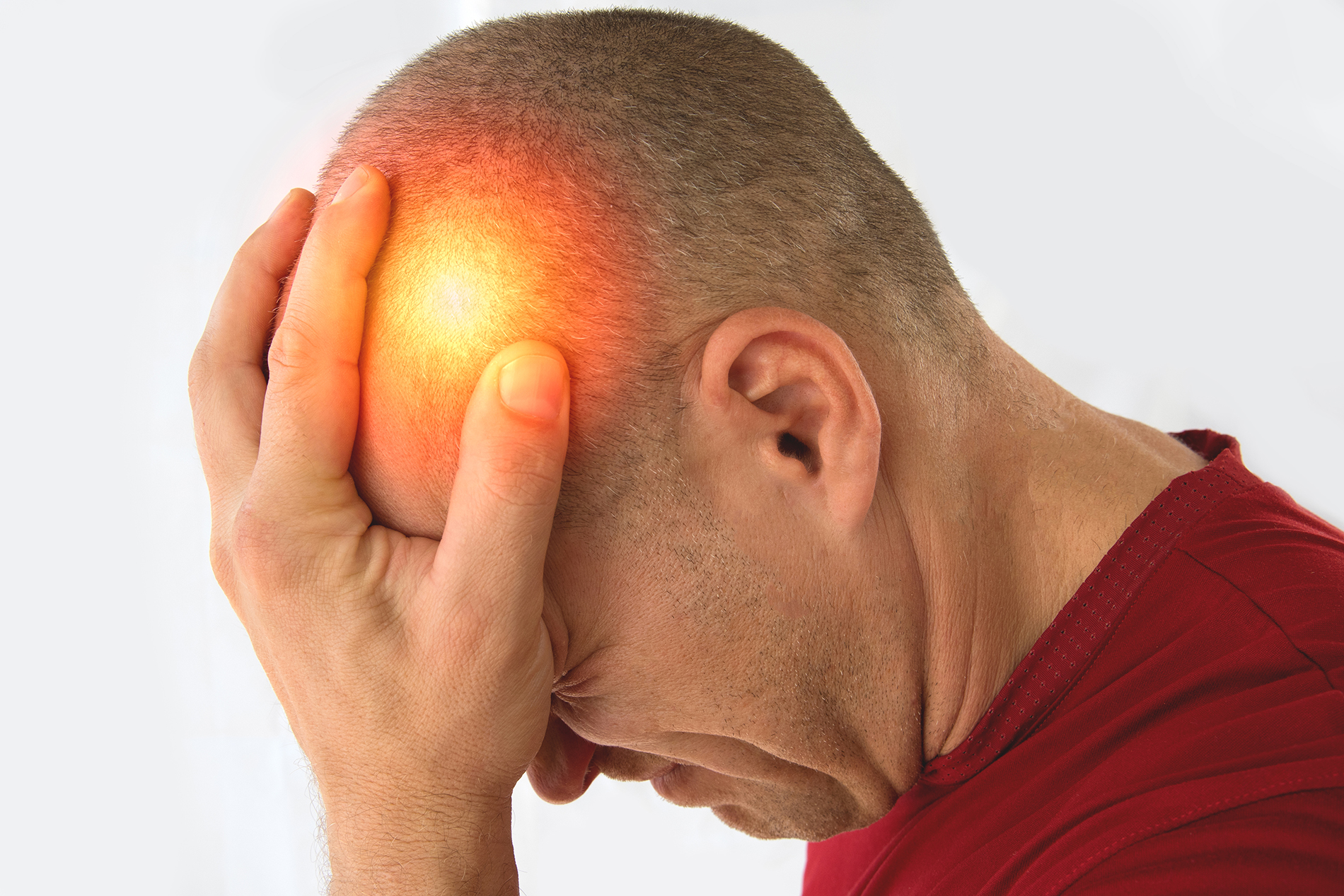 Man holding his head in pain with area lighted in red indicated a headache