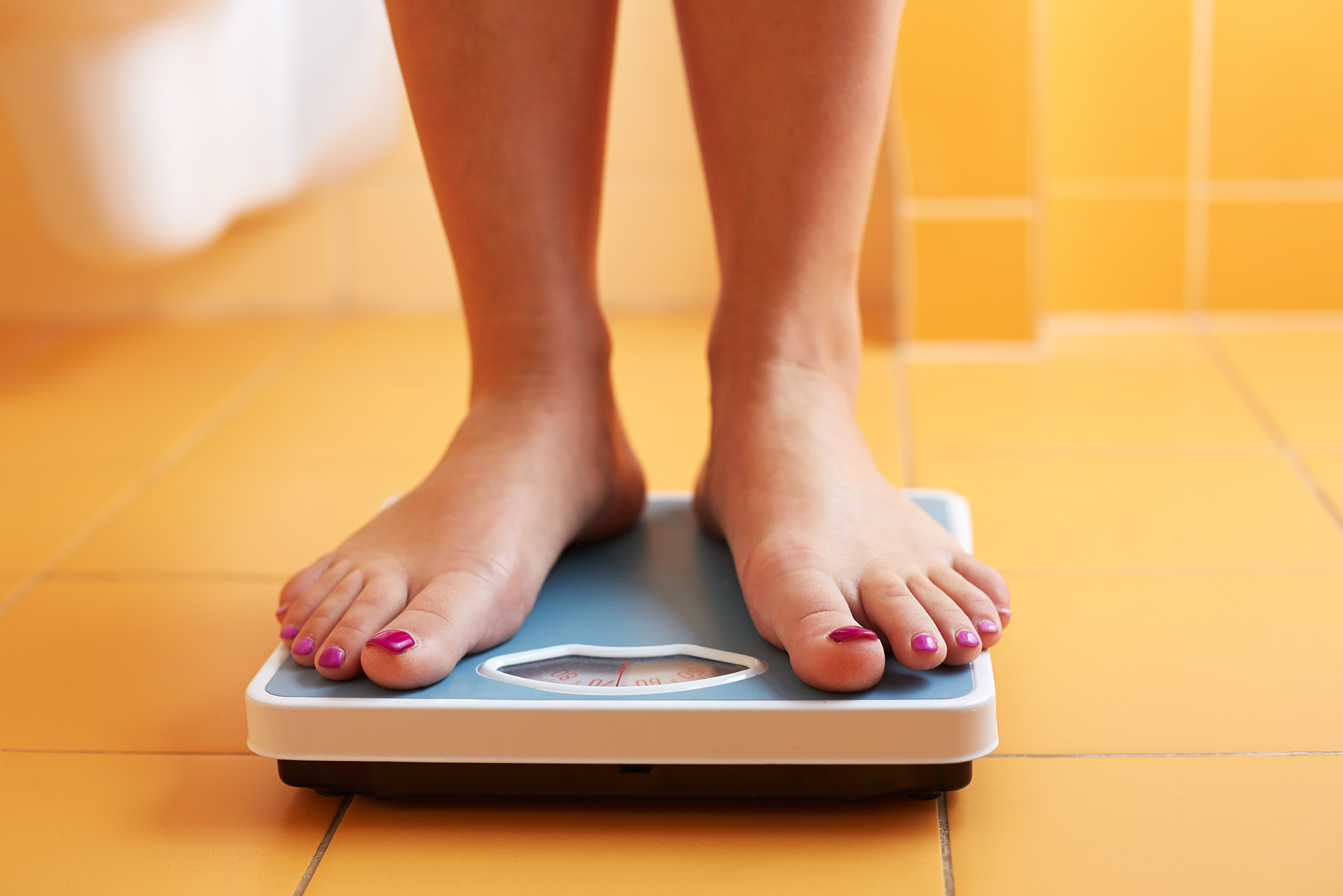 Woman's feet standing on scale in bathroom