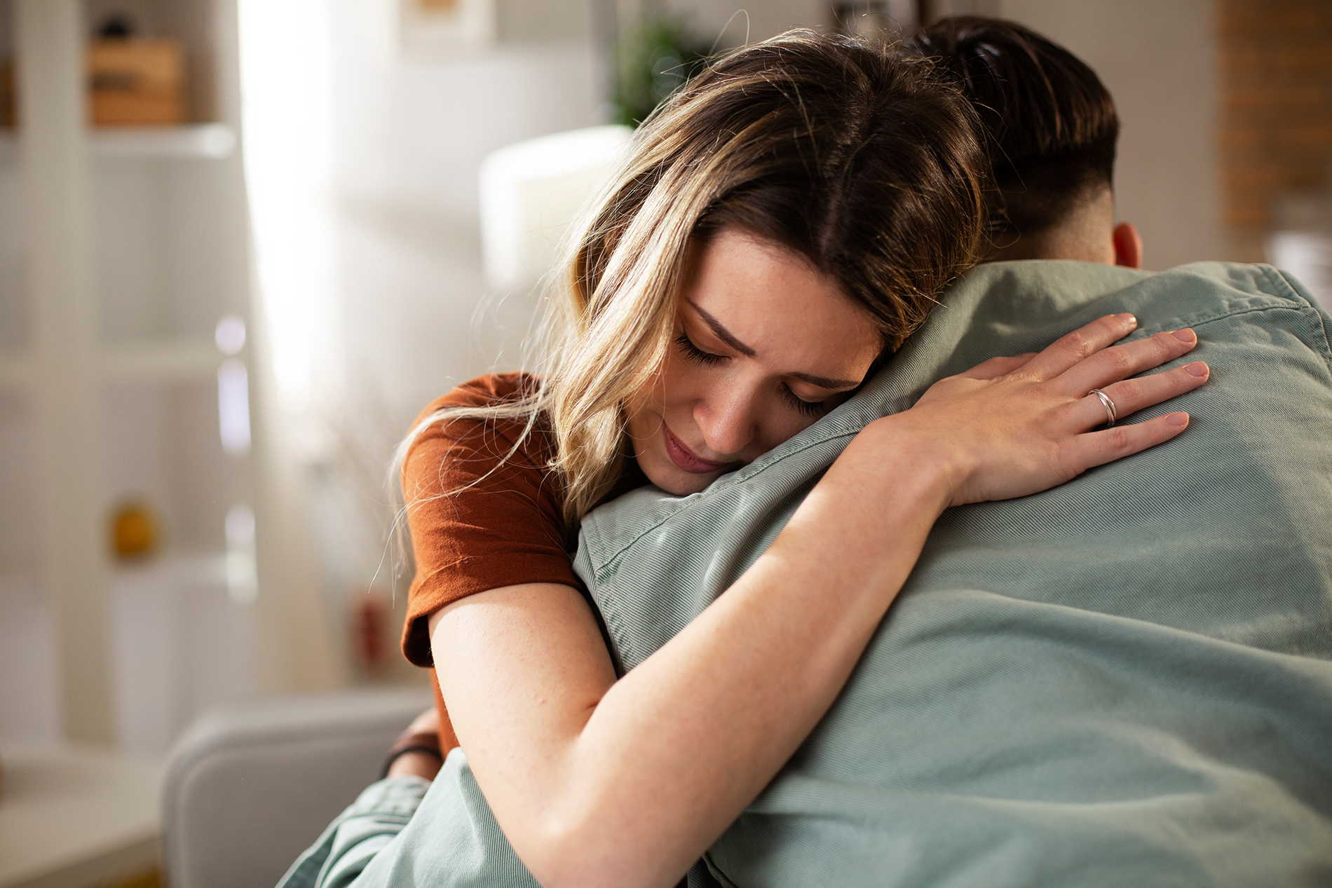Sad young couple hugging on couch