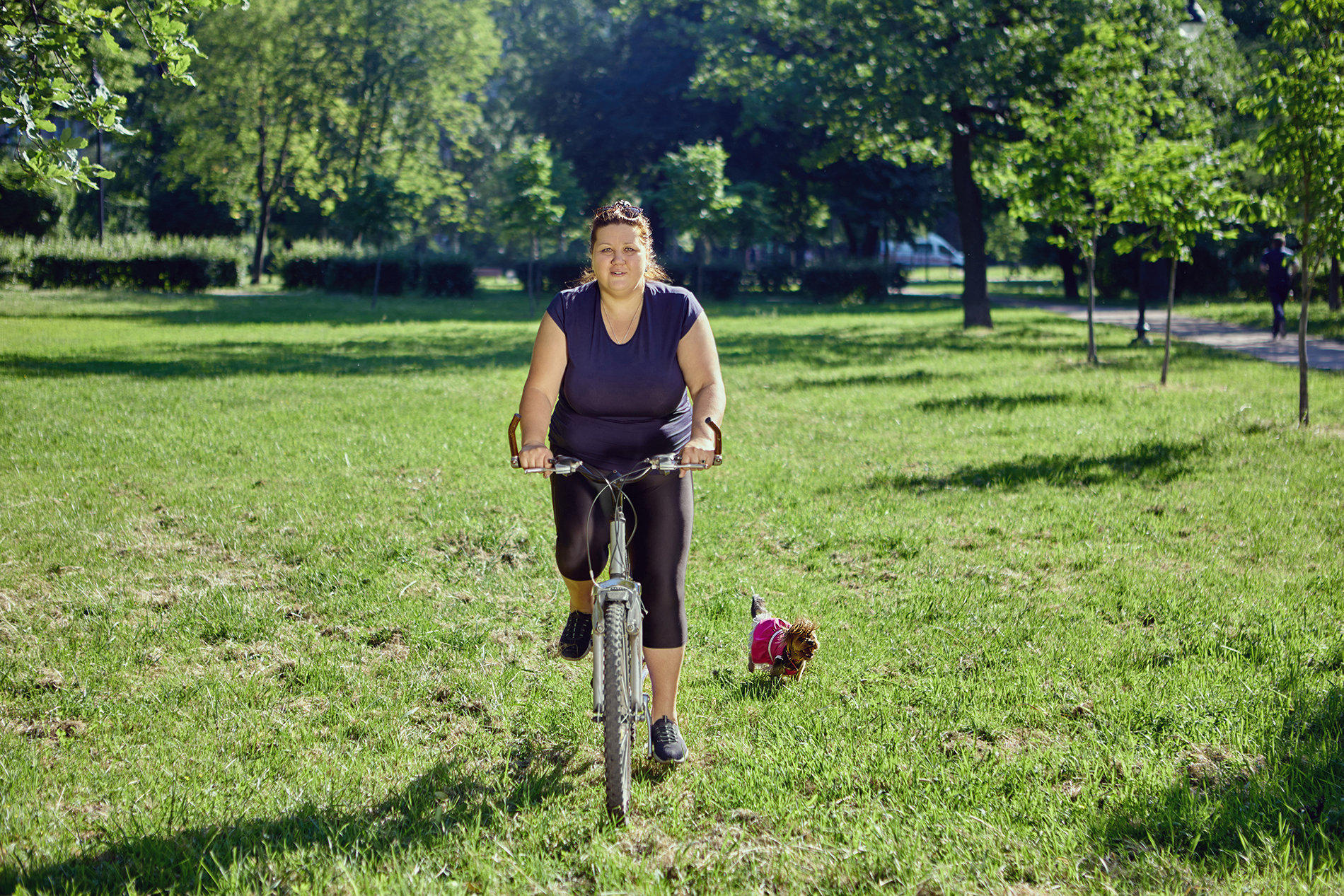 Overweight woman riding bicycle outdoors