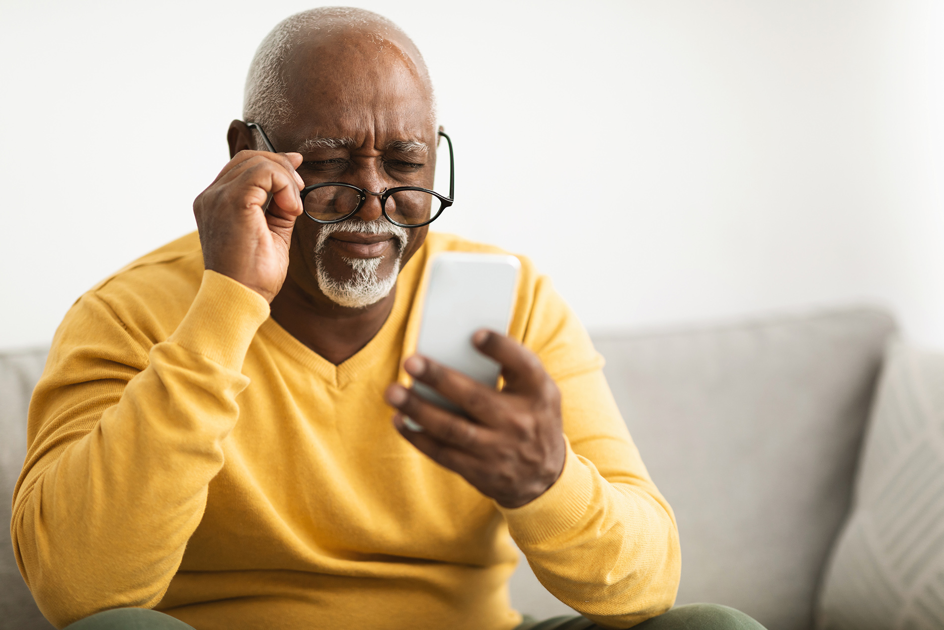 Older black man with poor vision looking at cell phone