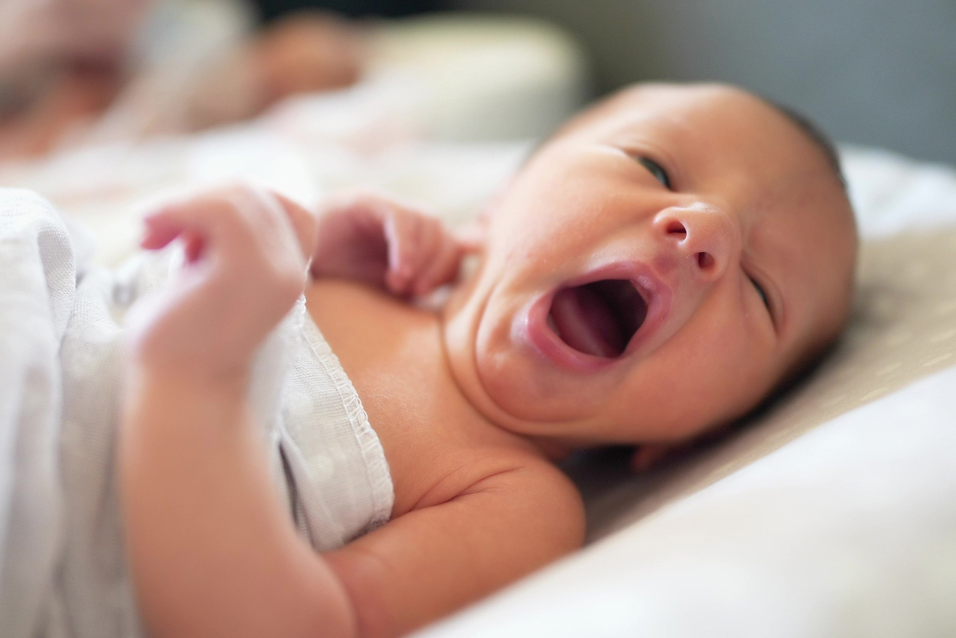 Swaddled newborn yawning