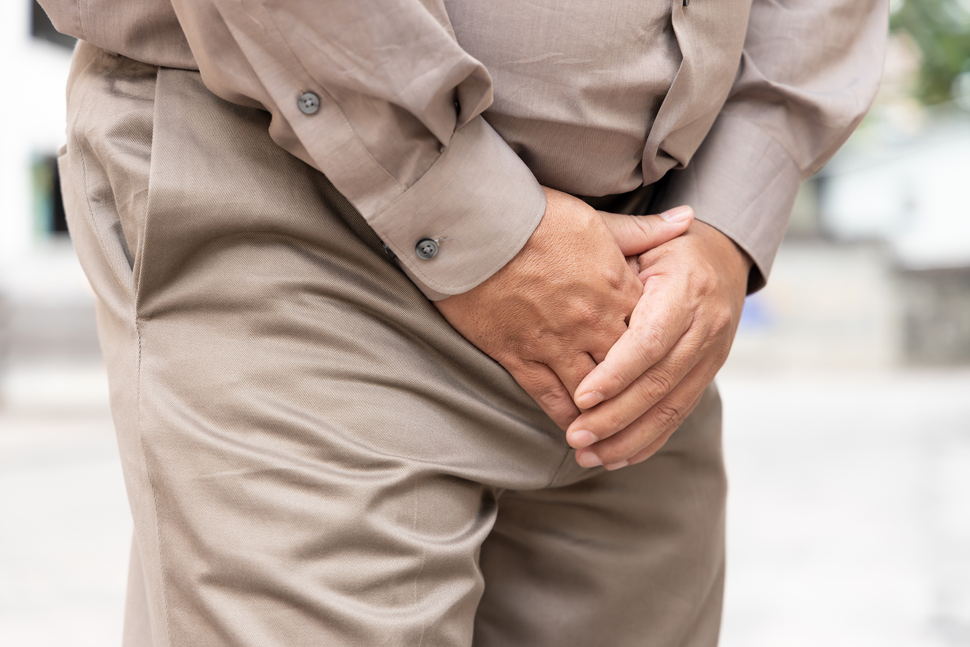 Older male in khaki pants with hands covering his crotch