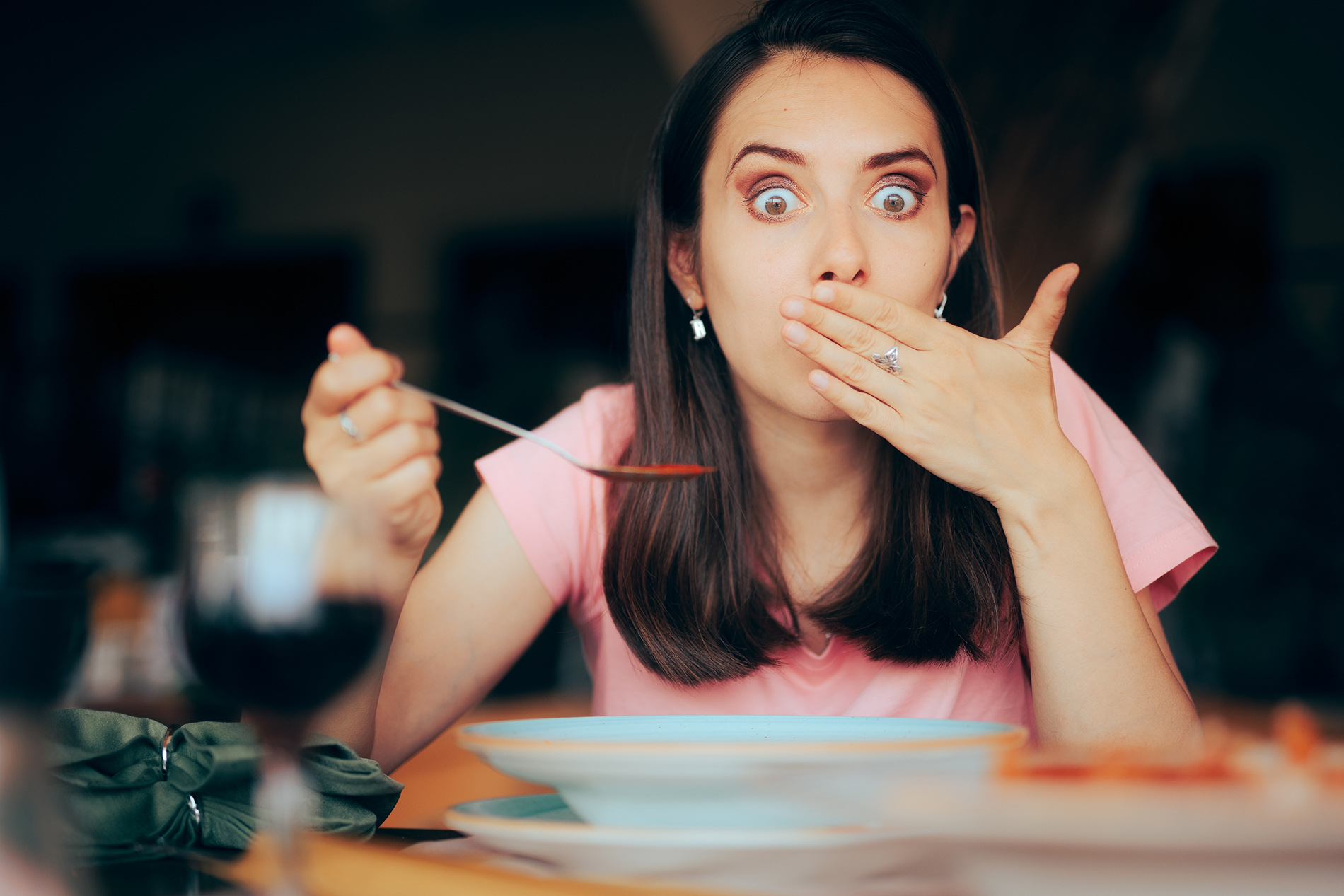 Young  woman looking surprised after hiccuping at the dinner table