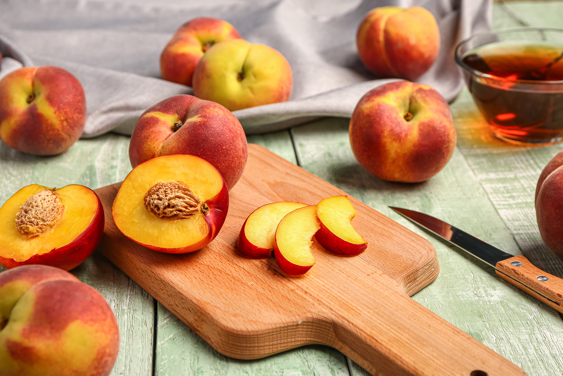 whole and cut peaches on cutting board