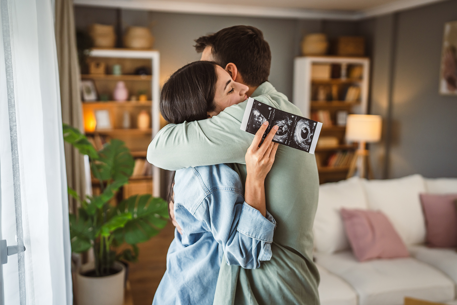 Young couple holding ultrasound photos of baby