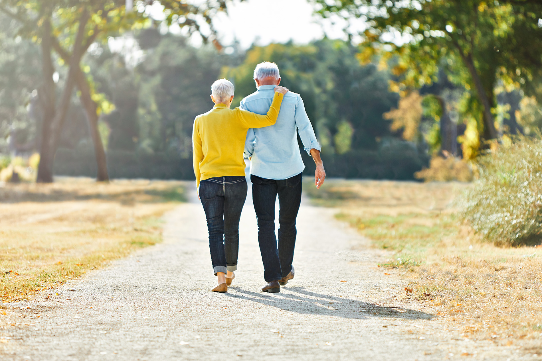 Active couple with grey hair walking down a long driveway