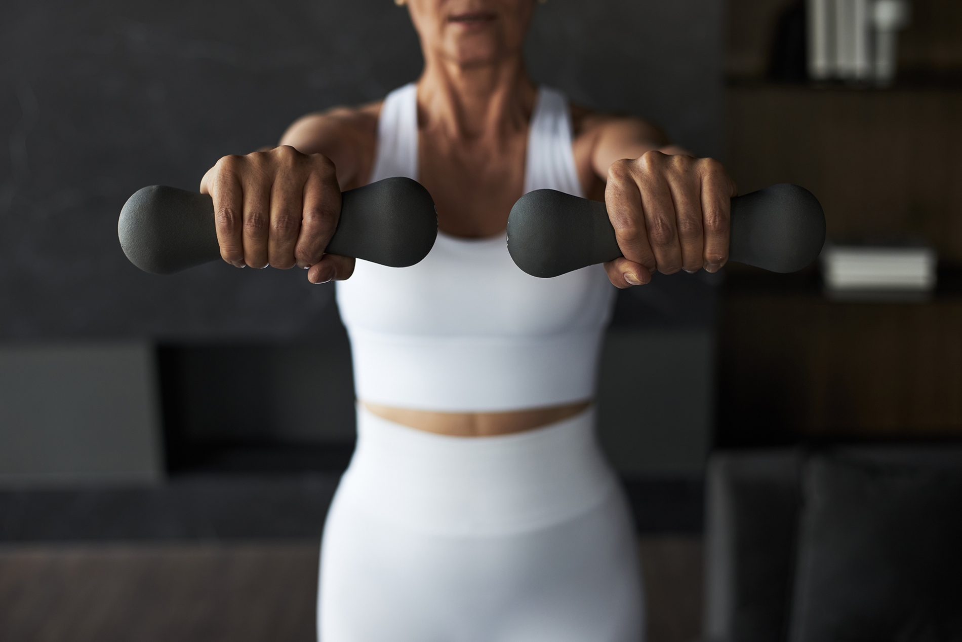 Middle aged woman holding free weights in shoulder extension