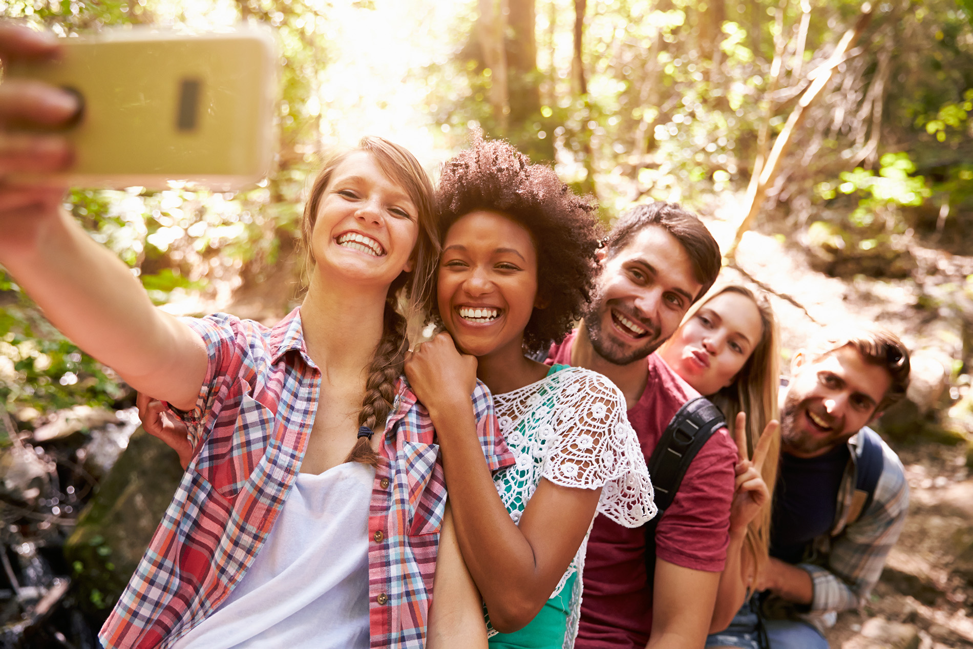 Group of young adults taking a photo while walking in the woods