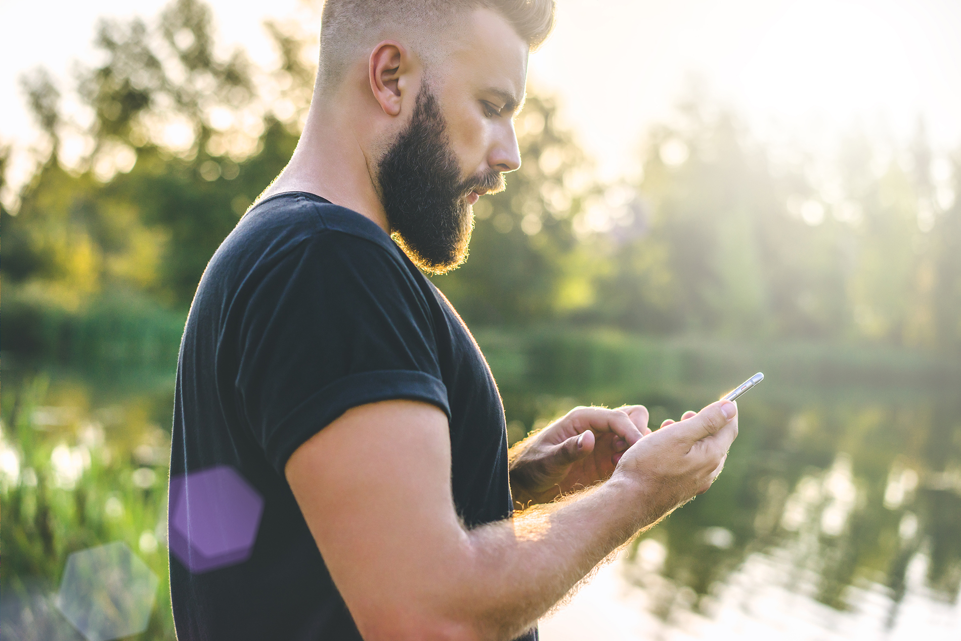 Bearded white man outside looking down at his mobile phone