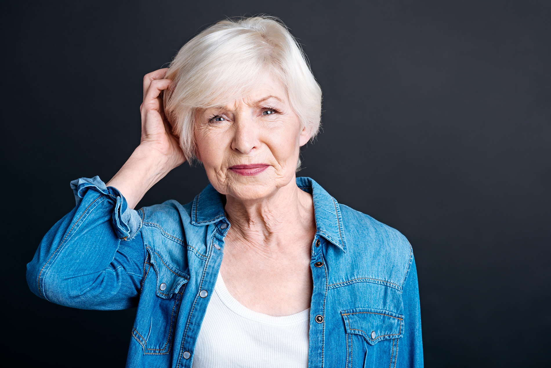 Older woman in blue shirt touching her head