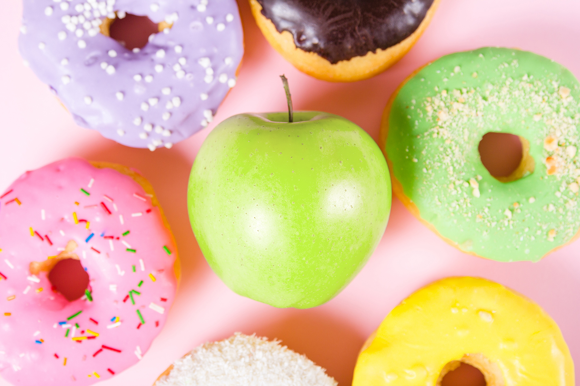 Green apple surrounded by doughnuts