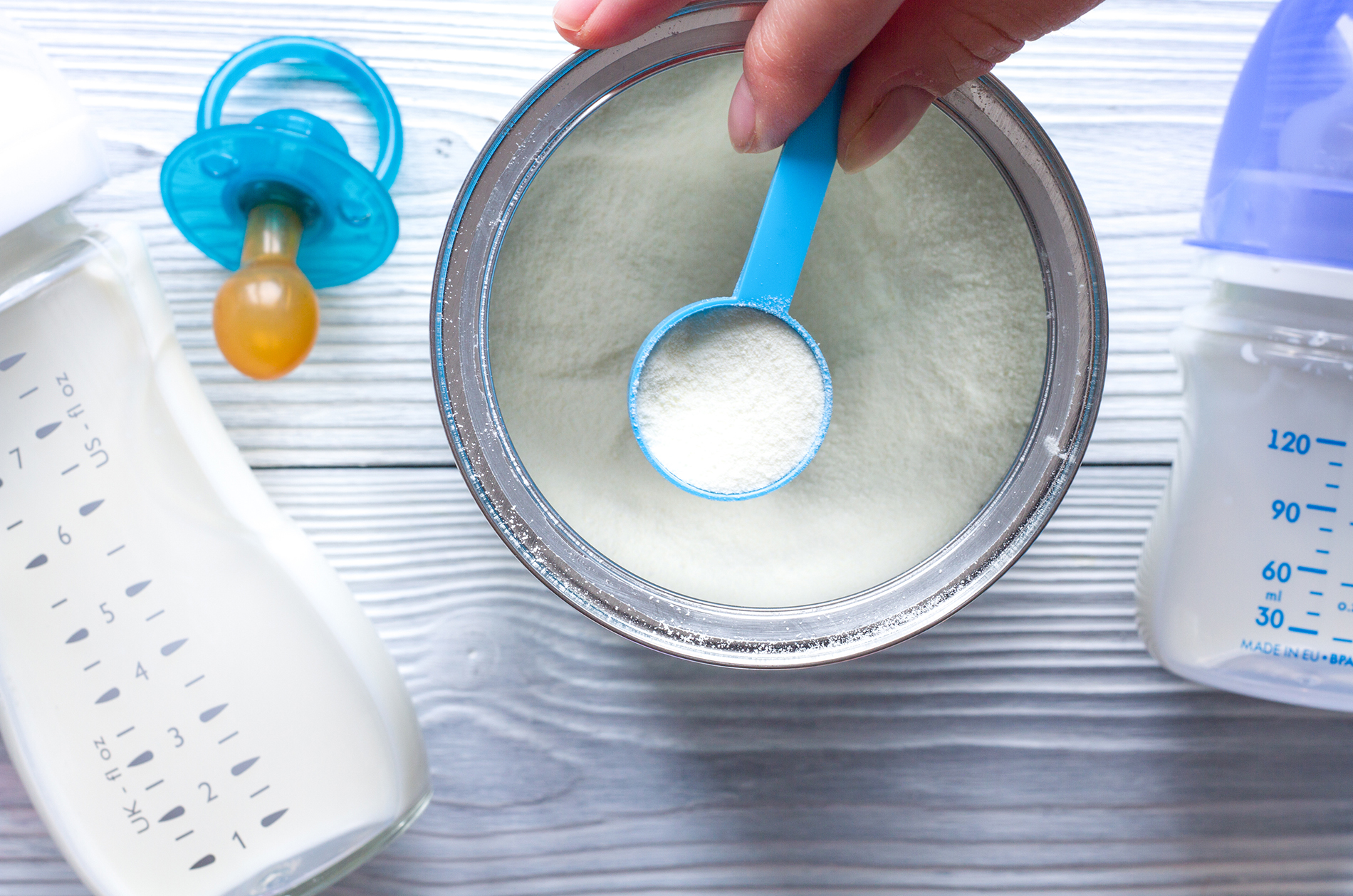 Baby formula can, baby bottle and pacifier on table. 