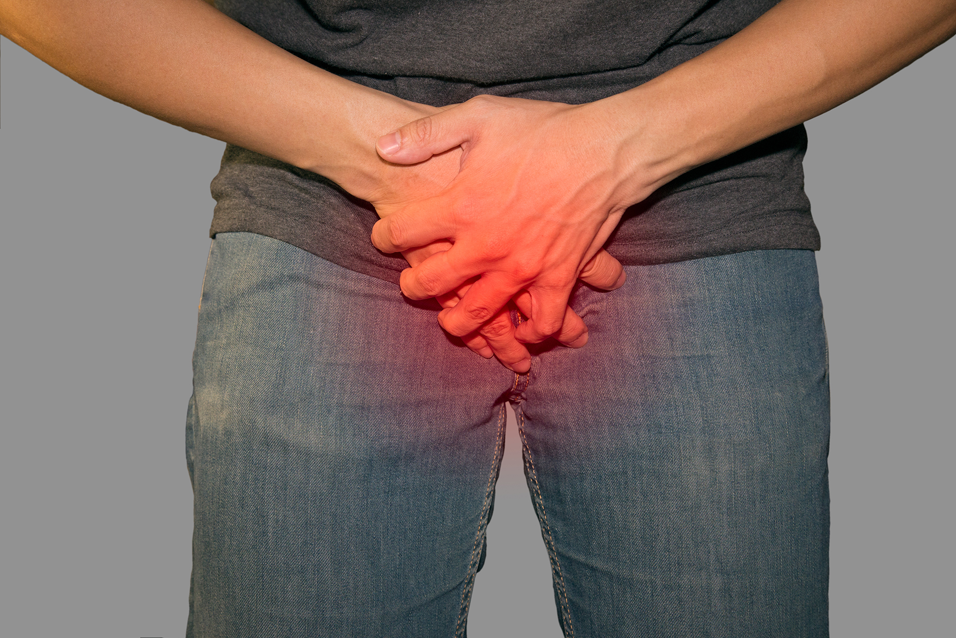 Young man wearing jeans holding his crotch in discomfort