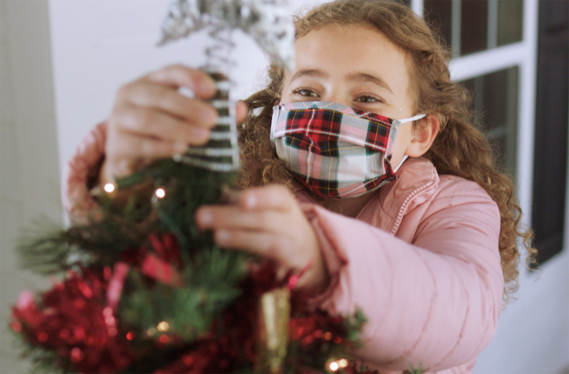 young girl in mask decorating for Christmas