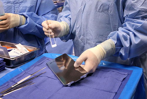 Dr. Engh picking up GammaTile with forceps in surgery