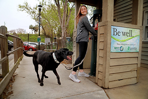 Woman with dog at Be Well water fountain in Riverwalk Park